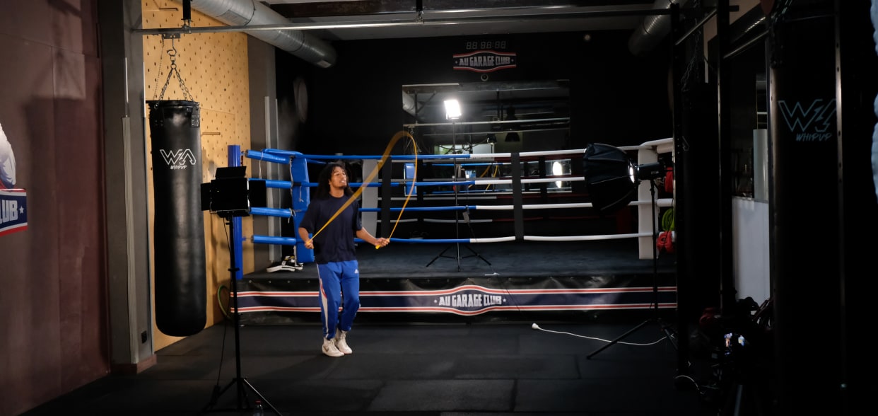 Coach jumping rope in a boxing gym in front of lights and a camera during a tutorial shoot